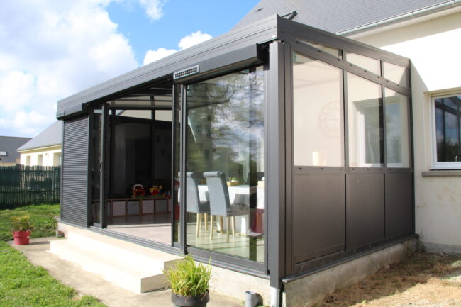 Véranda aluminium anthracite équipée de volets roulants solaires, fabrication ALUGLASS